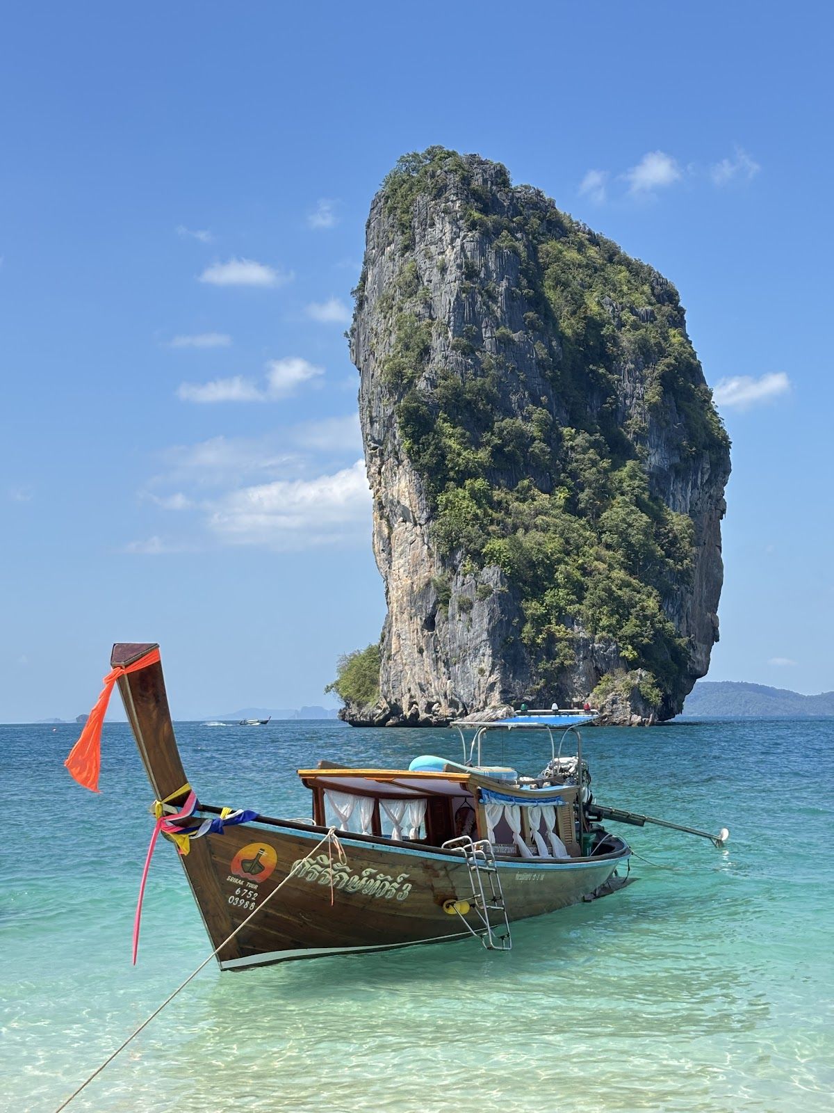 Longtail boats moored at Ao Nang beach in Krabi with limestone karst islands visible offshore