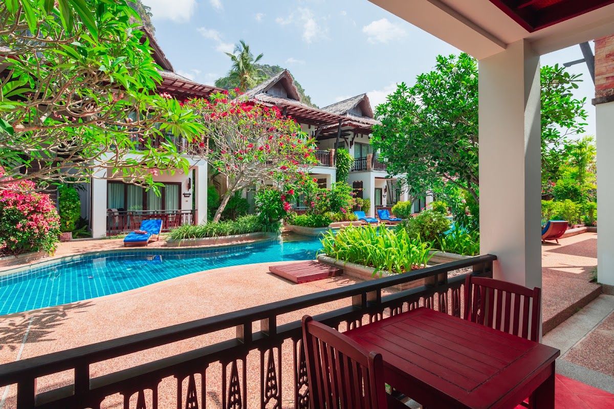 Pool and tropical gardens at Railay Village Resort and Spa with limestone cliffs rising above the Railay peninsula in Krabi